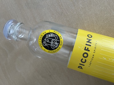 Imagen de una botella de vino vacía con una pegatina con gota de resina